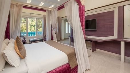 Luxurious bedroom at DLS Tehri Club Resort with a four-poster bed and elegant decor.